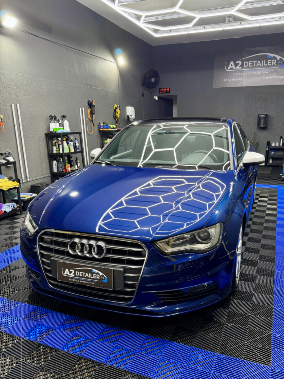 Audi azul em box premium com reflexo da iluminação no capô